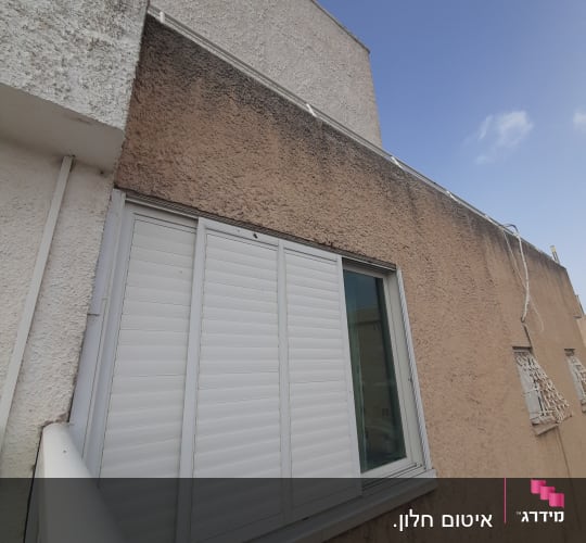 חלון עם תריסים סגורים על קיר חיצוני